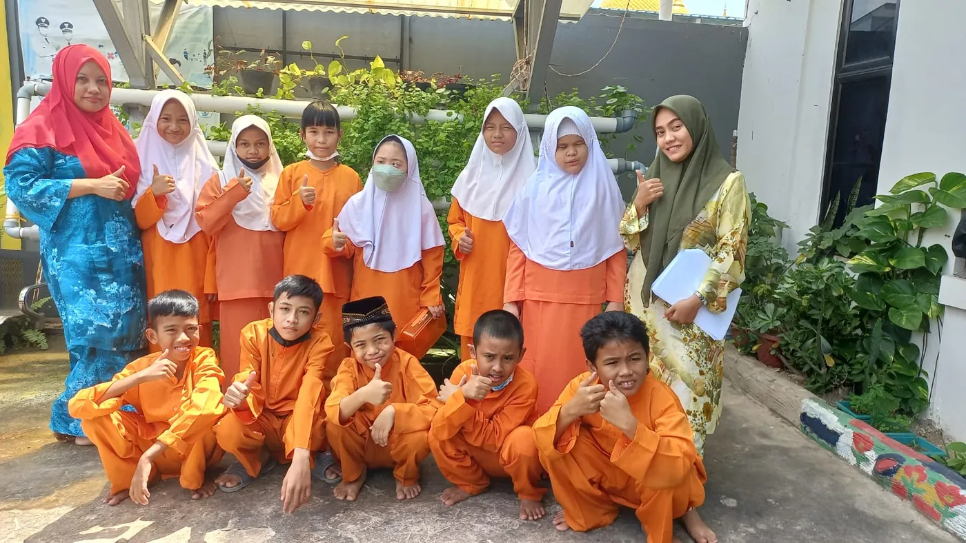 Siswa SLB Anak Brilliant bersama guru, tersenyum dan mengacungkan jempol